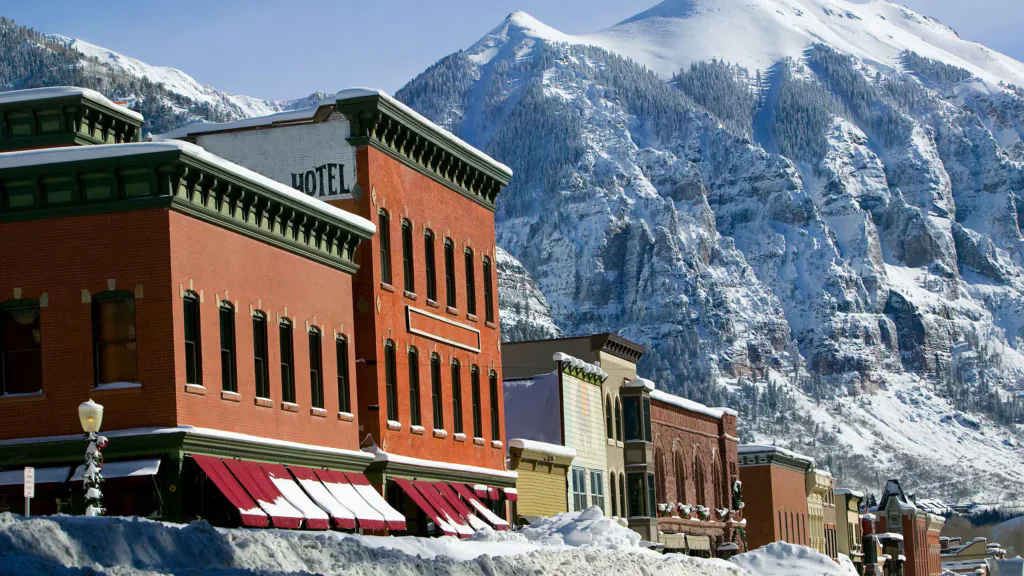 Historic brick building backed by snow-covered Colorado mountains